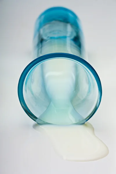 Mjölk Som Läckte Från Intresse Blå Glas Mot Vit Bakgrund — Stockfoto