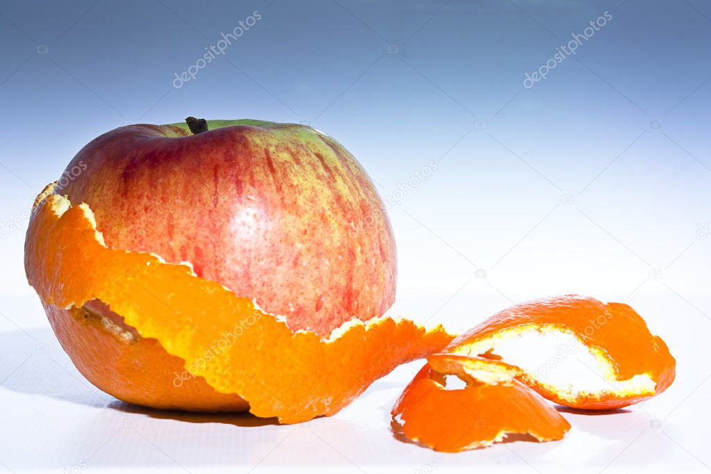 A aplle surprise inside the peel of an arange against a graduated backdrop