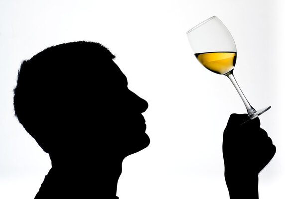 A man in silhouette tesing white wine