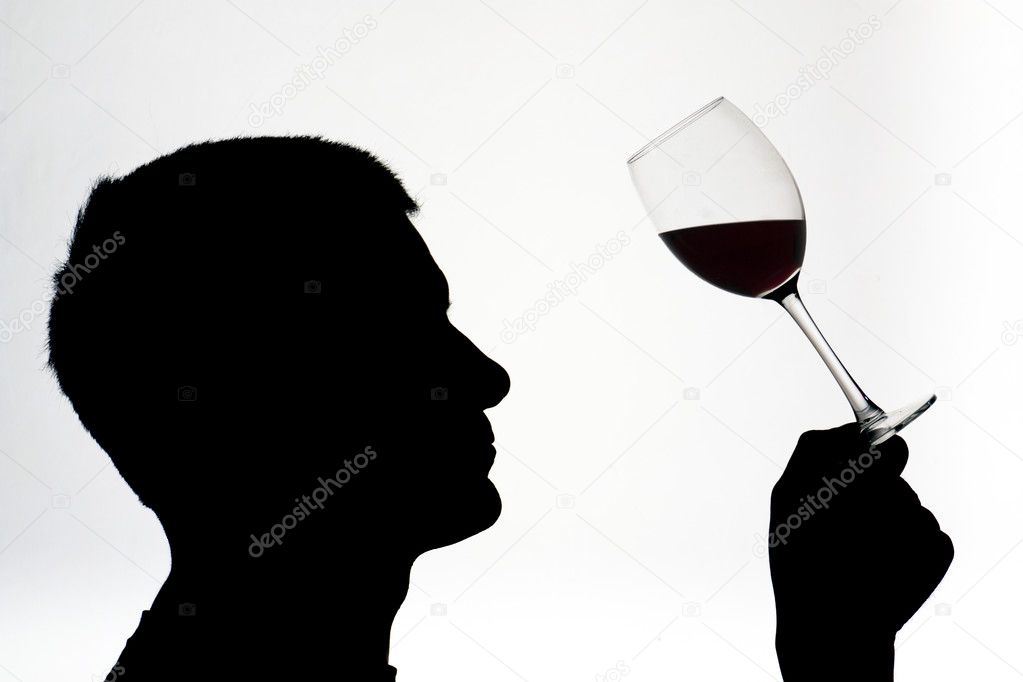 A man in silhouette testing red wine