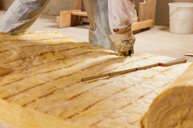 Man cutting insulation material for building clipart