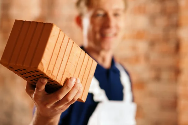 Bricklayer with brick at a — Stock Photo, Image