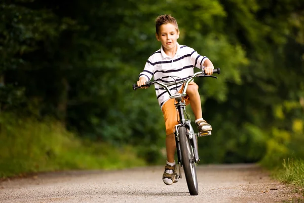 Menino montando sua bicicleta em um — Fotografia de Stock