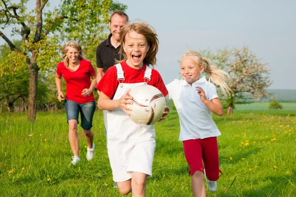 Glückliche Familie spielt Fußball — Stockfoto