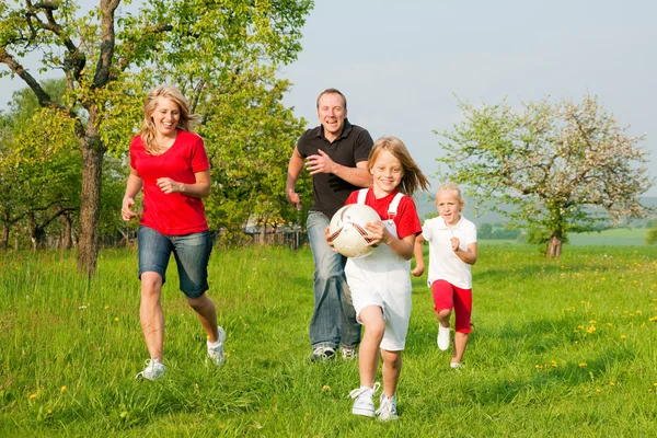Счастливая семья играет в футбол — стоковое фото