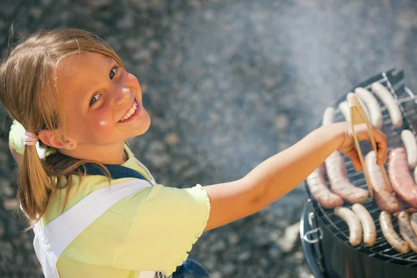 Маленькая девочка готовит мясо и — стоковое фото