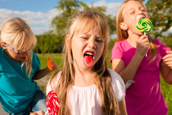 Três meninas comendo pirulitos, o — Fotografia de Stock
