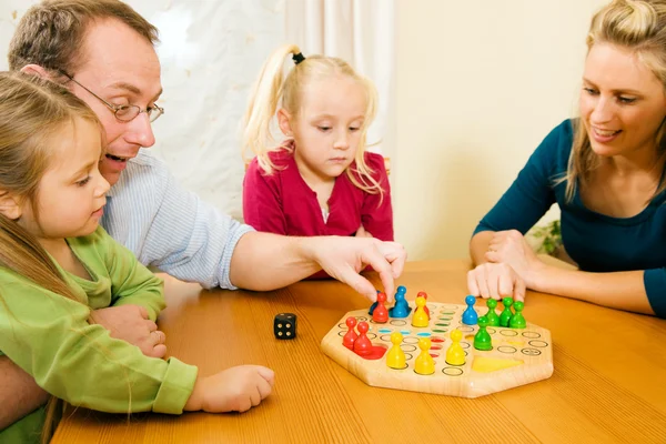 Семья играет в настольную игру в — стоковое фото