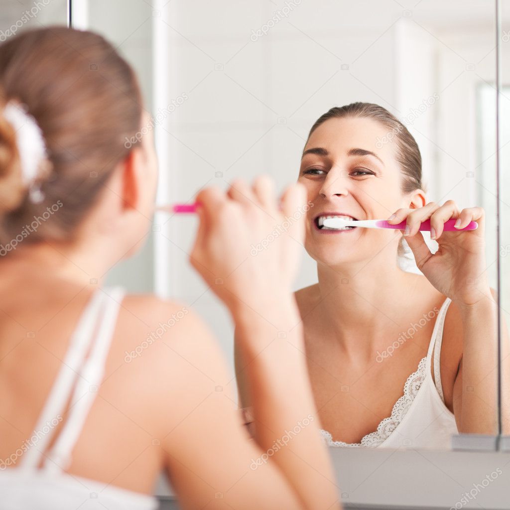 Young woman brushing teeth at wash bowl