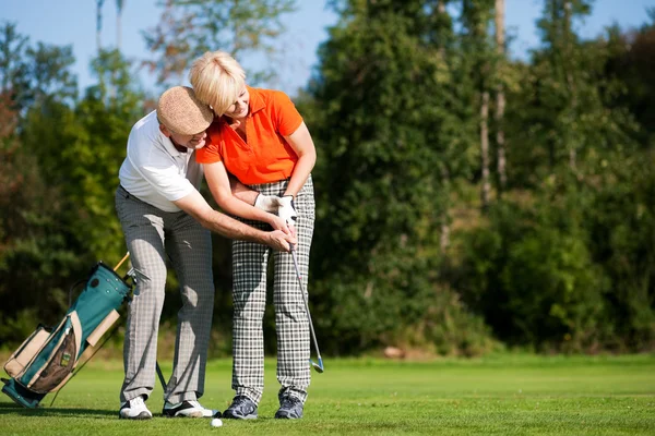 Senior couple playing golf on a — Stock Photo, Image