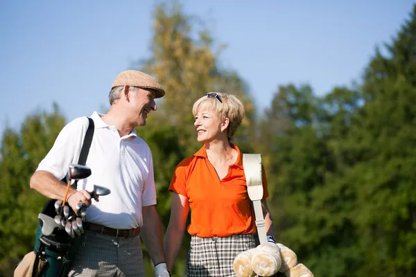 Senior couple playing golf on a — Stock Photo, Image