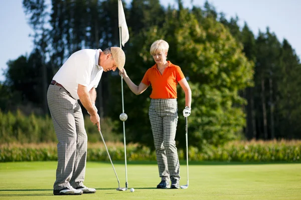 Старшая пара играет в гольф на — стоковое фото