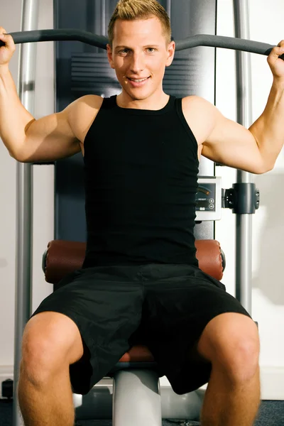 Junger Mann im Fitnessstudio beim Training seiner — Stockfoto