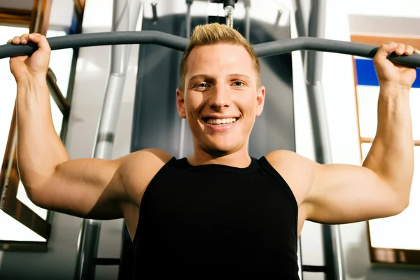 Young man in a gym training his — Stock Photo, Image