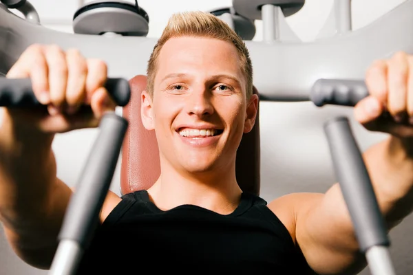 Junger Mann im Fitnessstudio beim Training seiner — Stockfoto