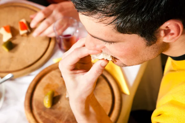 Young man eating a traditional — Stock Photo, Image