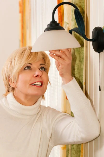Kvinna byta en glödlampa i — Stockfoto