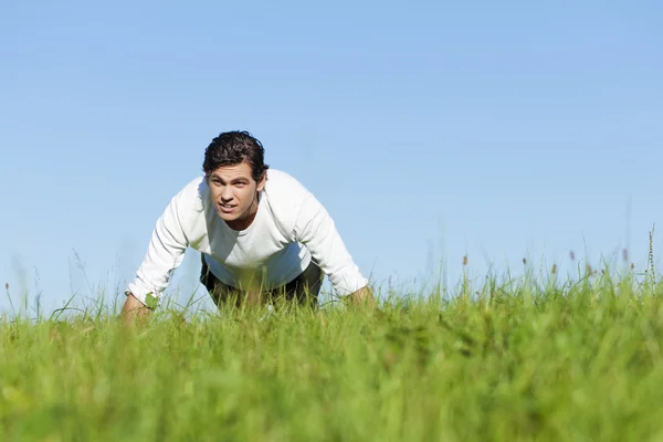Man doing push ups in summer grass — Stock Photo, Image