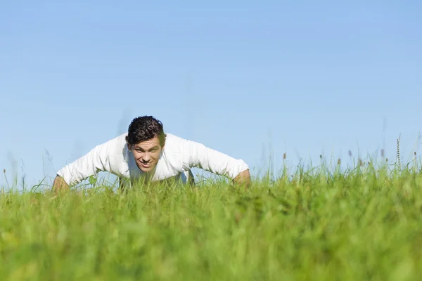 Man doing push ups in summer grass — Stock Photo, Image