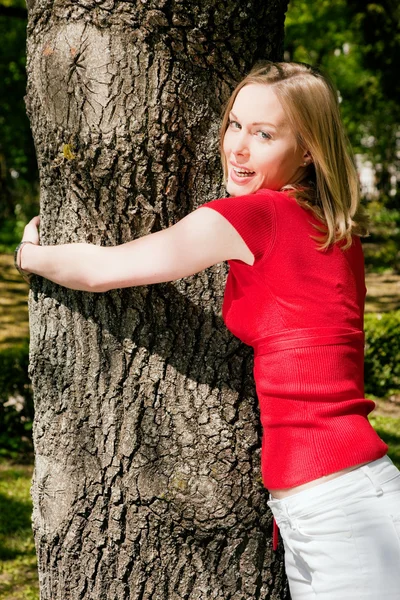 Menina abraçando uma árvore e — Fotografia de Stock