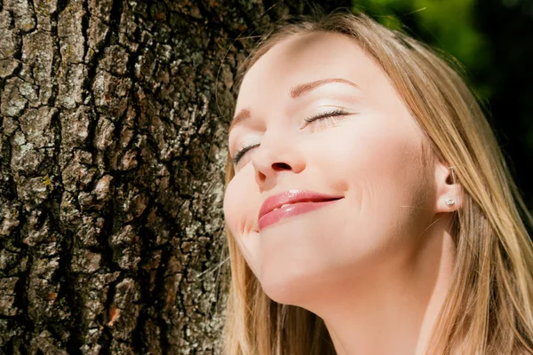 Mädchen kuschelt an einem Baum und — Stockfoto