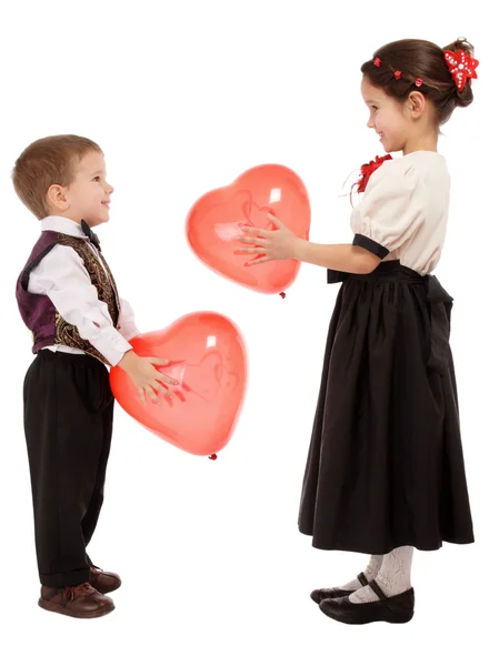 As crianças pequenas dão balões vermelhos um ao outro — Fotografia de Stock