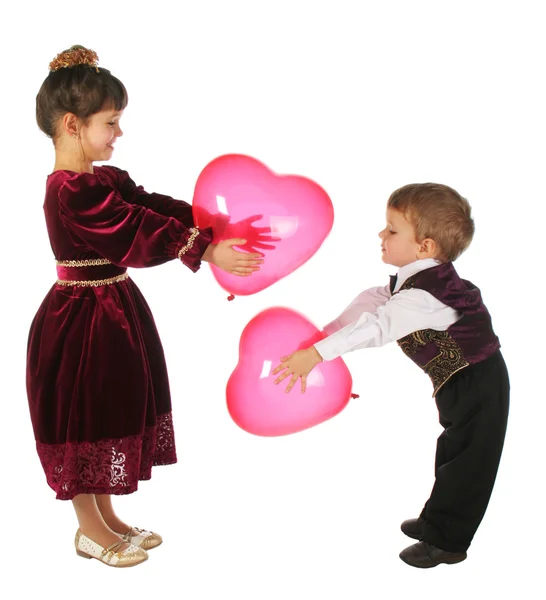 Menina e menino com balões vermelhos de coração — Fotografia de Stock