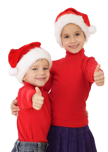 Crianças sorridentes em chapéus de Natal e polegares para cima sinal — Fotografia de Stock