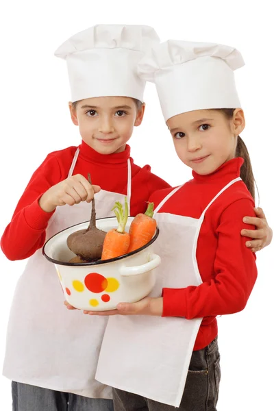 Dwa małe szef kuchenki trzymając garnek z warzywami — Zdjęcie stockowe