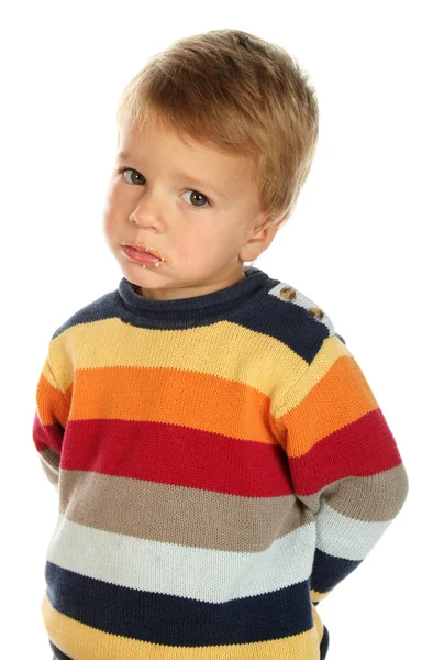 Zmatený chlapec v svetr s dort špinavé tváře — Stock fotografie