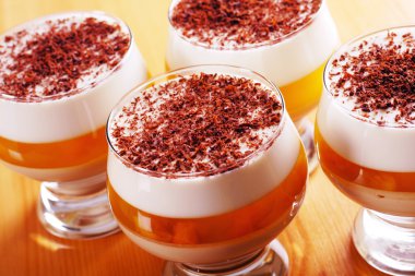 Multilayer gelatin dessert with chocolate, cream and dried apricots jelly in glasses clipart