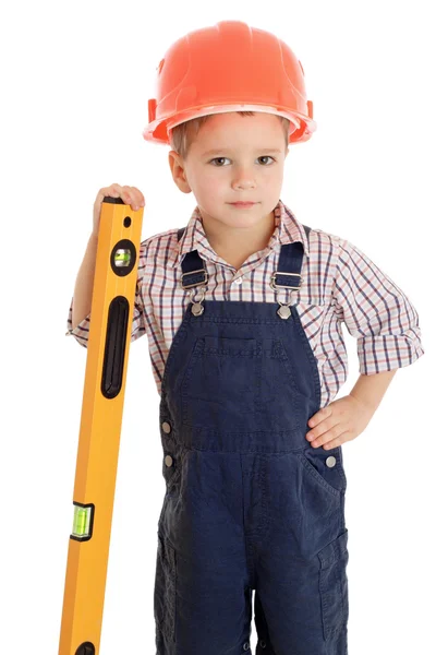Маленький строитель в комбинезоне и шлеме с жидким уровнем — стоковое фото