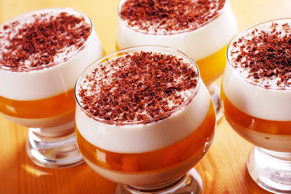 stock image Multilayer gelatin dessert with chocolate, cream and dried apricots jelly in glasses