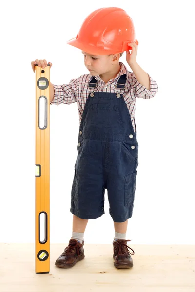 Маленький строитель с уровнем жидкости, стоящий на деревянном полу — стоковое фото