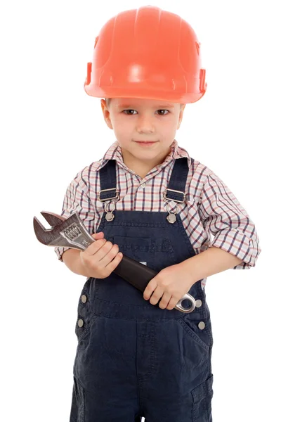 Маленький строитель в комбинезоне и шлеме с гаечным ключом — стоковое фото