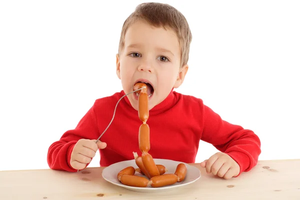 Мальчик ест сосиски — стоковое фото