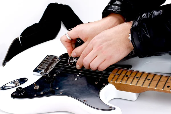 Person tuning a guitar from its headstock over white background — Stock Photo, Image