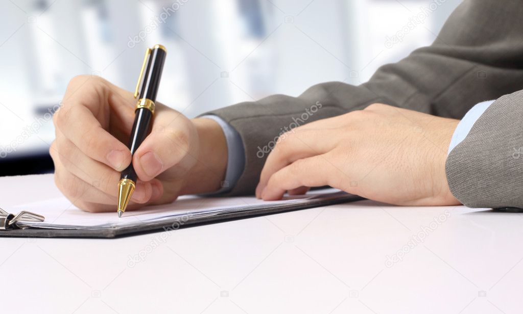 Close-up of business person hand with pen over document