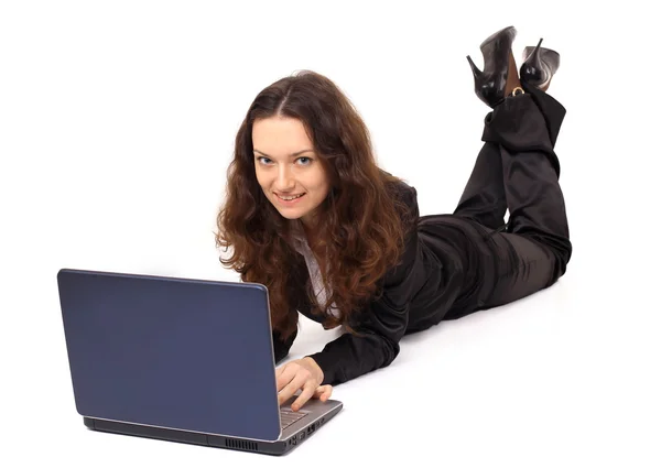 Lachende meisje werkt met de laptop op de vloer liggen — Stockfoto