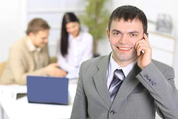 Молодой бизнесмен разговаривает по мобильному телефону в офисном коридоре . — стоковое фото