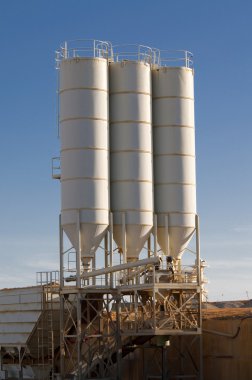 Three silos of sand in a gravel pit operation clipart