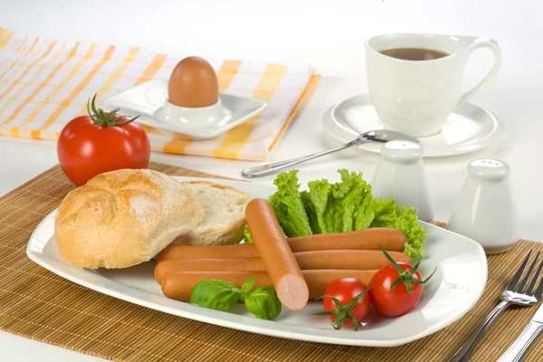 Salsichas de café da manhã, tomate, ovo e xícara de chá — Fotografia de Stock