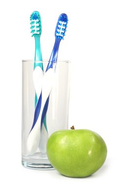 Зубные щетки в стакане и яблоко clipart