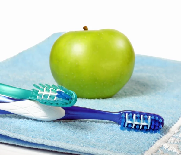 Зубные щетки в стакане и яблоко — Stock Photo, Image
