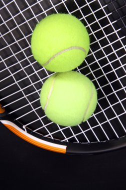 Tennis racket and balls on black clipart