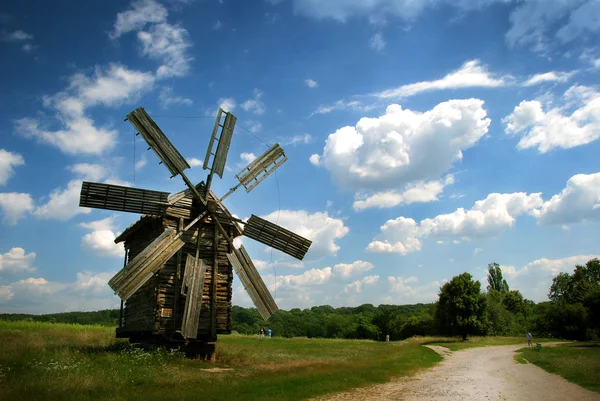 stock image Windmill with the blue clouds and green grass