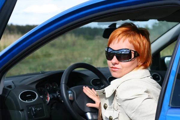 Kızıl saçlı kadın güneş gözlüğü mavi otomobil — Stok fotoğraf