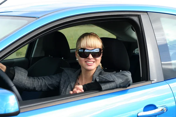 Młoda blond kobieta w niebieskim samochodem w okulary — Zdjęcie stockowe