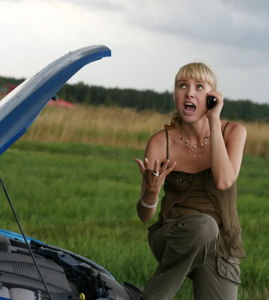 Junge blonde Frau mit ihrem kaputten Auto. Das Mädchen ist wütend — Stockfoto