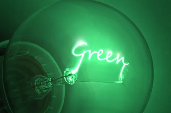 stock image Close up of green light bulb with the illuminated filament spelling the word 'Green'